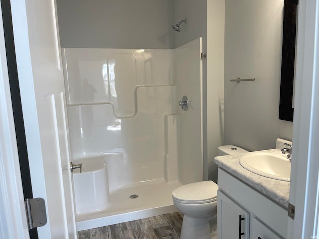 bathroom featuring wood-type flooring, vanity, toilet, and walk in shower