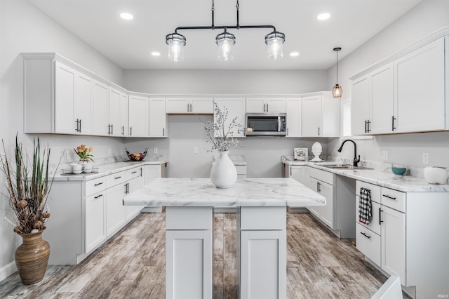 kitchen with pendant lighting, a center island, white cabinetry, and sink