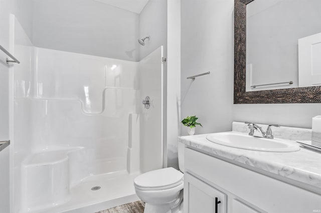 bathroom with a shower, hardwood / wood-style floors, vanity, and toilet