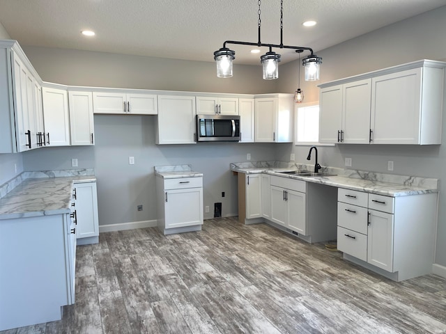 kitchen featuring white cabinets, hardwood / wood-style flooring, hanging light fixtures, and sink