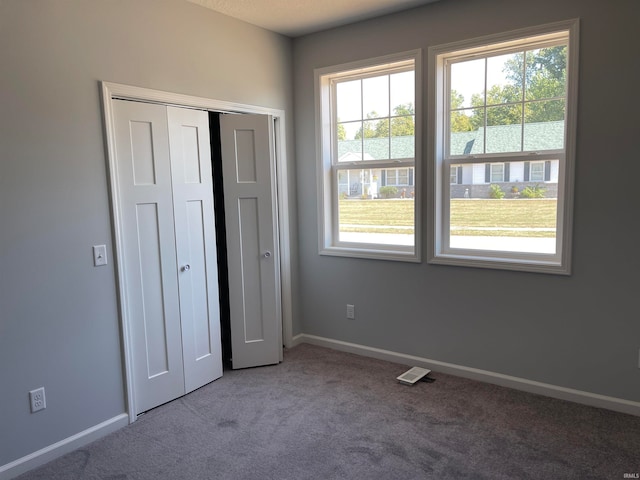 unfurnished bedroom featuring carpet floors, a closet, and multiple windows