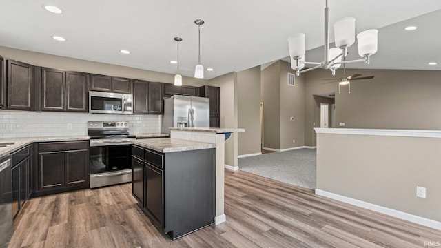 kitchen featuring appliances with stainless steel finishes, light wood-type flooring, backsplash, a kitchen island, and hanging light fixtures