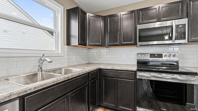 kitchen featuring dark brown cabinetry, sink, appliances with stainless steel finishes, and tasteful backsplash