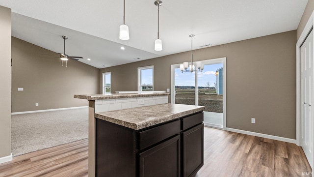 kitchen featuring pendant lighting, a center island, ceiling fan with notable chandelier, vaulted ceiling, and light wood-type flooring