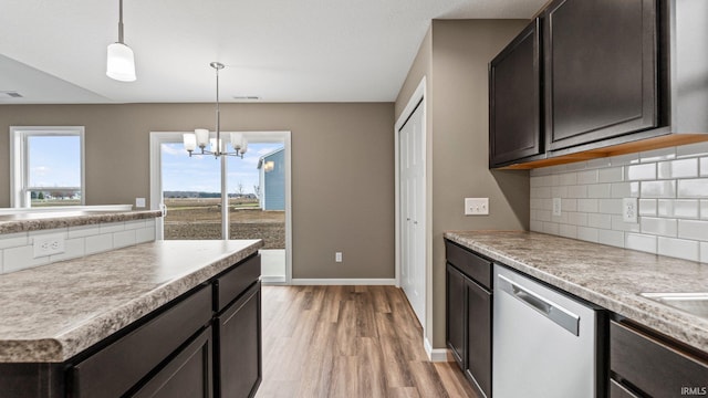 kitchen with hanging light fixtures, stainless steel dishwasher, backsplash, a chandelier, and light wood-type flooring