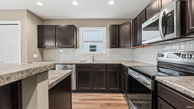 kitchen with dark brown cabinets, sink, appliances with stainless steel finishes, and light hardwood / wood-style flooring