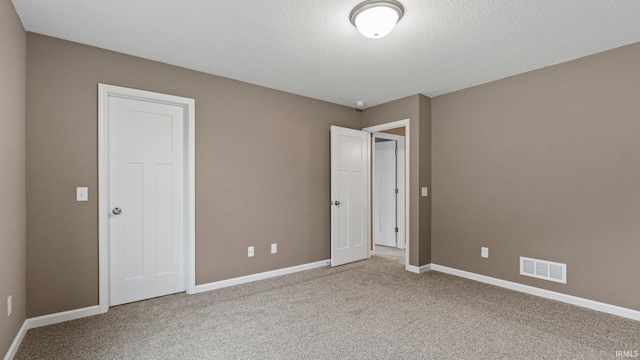 unfurnished bedroom with a textured ceiling and carpet floors