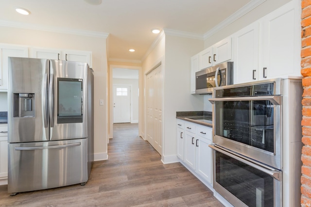 kitchen with white cabinetry, ornamental molding, stainless steel appliances, and light wood-type flooring