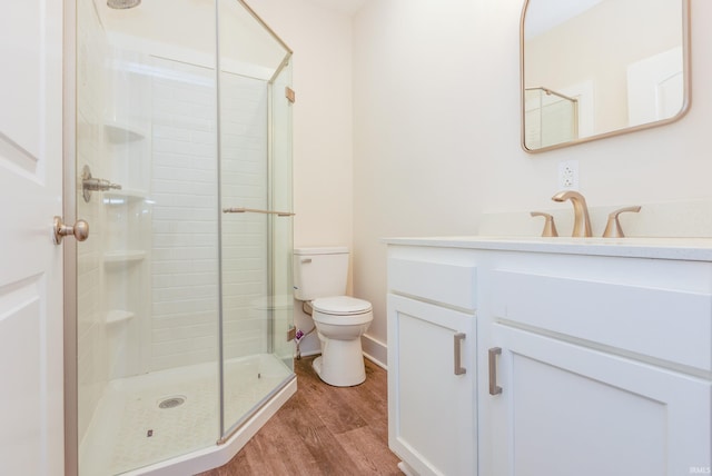 bathroom with vanity, hardwood / wood-style floors, a shower with shower door, and toilet