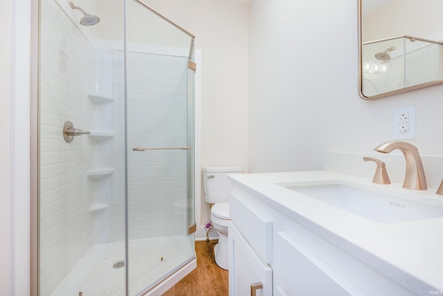 bathroom with vanity, a shower with shower door, hardwood / wood-style floors, and toilet