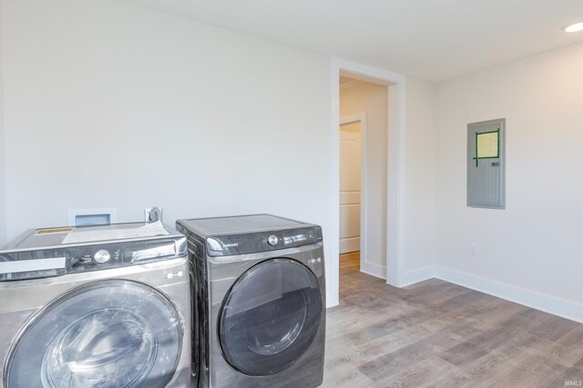 washroom featuring light hardwood / wood-style flooring, washing machine and dryer, and electric panel