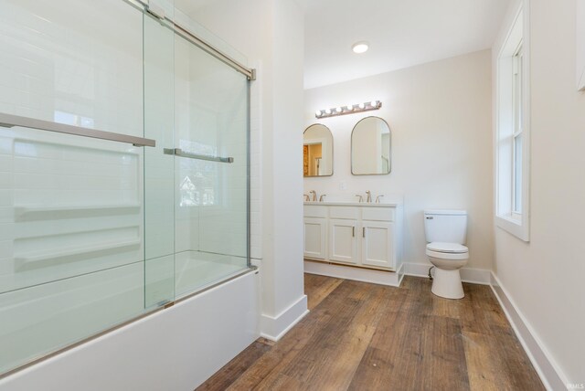 full bathroom featuring toilet, vanity, combined bath / shower with glass door, and hardwood / wood-style floors