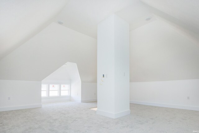 additional living space featuring lofted ceiling and light carpet