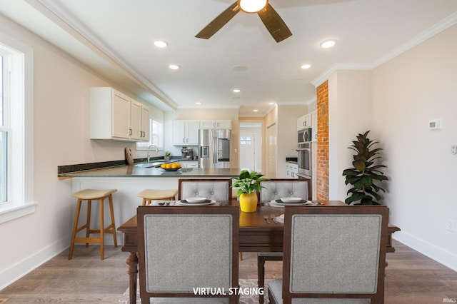 dining area with hardwood / wood-style floors, crown molding, sink, and ceiling fan