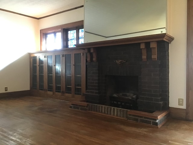 unfurnished living room with hardwood / wood-style floors, a brick fireplace, and crown molding