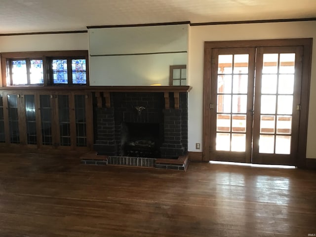 unfurnished living room with dark hardwood / wood-style flooring, ornamental molding, a fireplace, and french doors