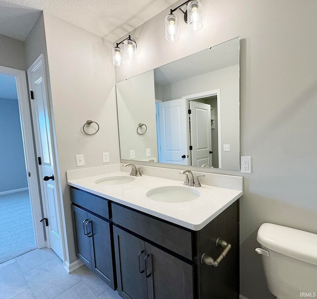 bathroom with vanity, toilet, tile patterned flooring, and a textured ceiling