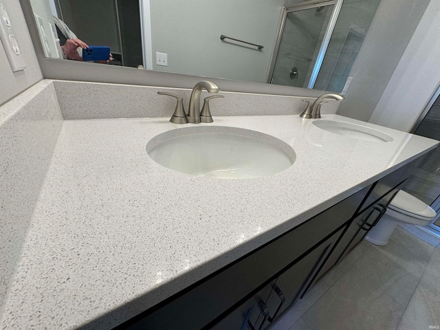 bathroom featuring a shower with door, vanity, and toilet