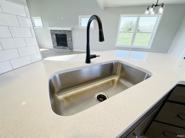 room details featuring sink, a fireplace, and light stone countertops