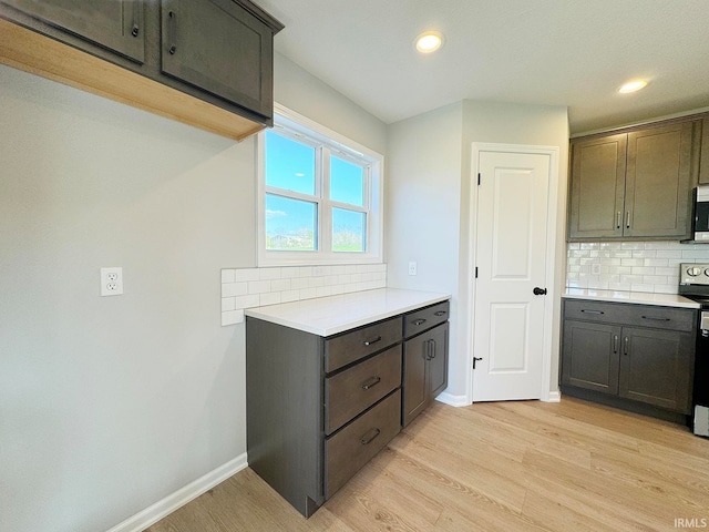 kitchen with dark brown cabinetry, light hardwood / wood-style floors, decorative backsplash, and stove