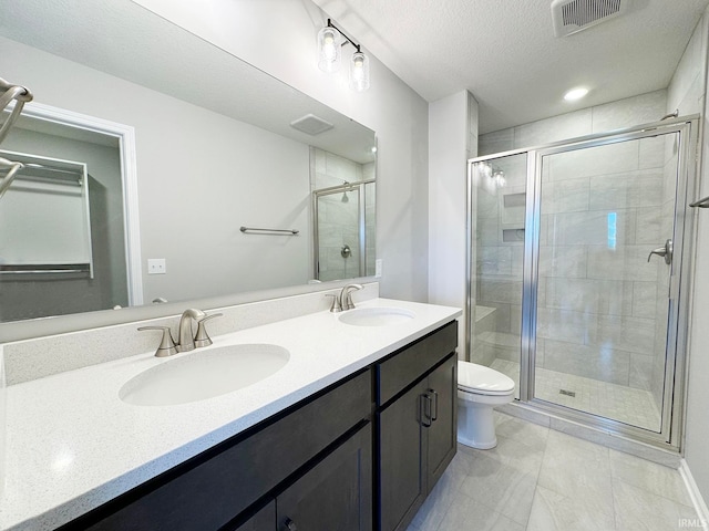 bathroom featuring walk in shower, vanity, toilet, and a textured ceiling