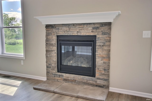 room details featuring a stone fireplace, crown molding, and hardwood / wood-style floors