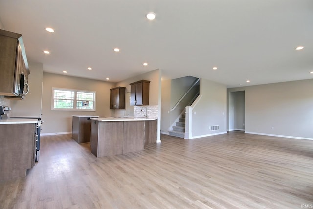 kitchen with sink, light hardwood / wood-style flooring, stainless steel appliances, and backsplash