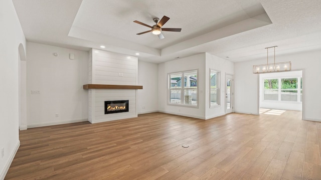 002 Ln 520 Lake James Unit 2, Fremont, IN 46737 - unfurnished living room with a textured ceiling, a fireplace, a ceiling fan, light wood-type flooring, and a tray ceiling