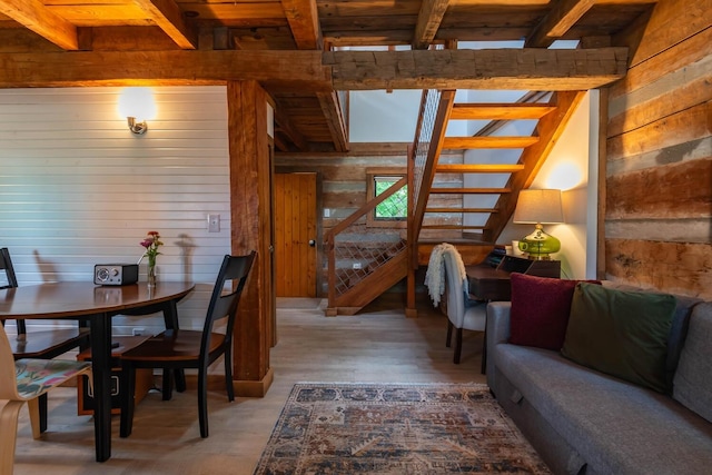 dining area featuring wood walls, light hardwood / wood-style flooring, beamed ceiling, and wood ceiling