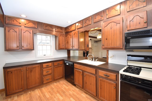 kitchen featuring black appliances, sink, and light hardwood / wood-style flooring