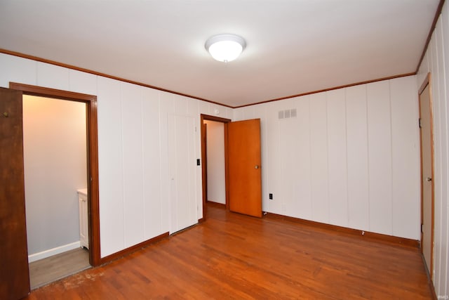 unfurnished bedroom with wood-type flooring and crown molding