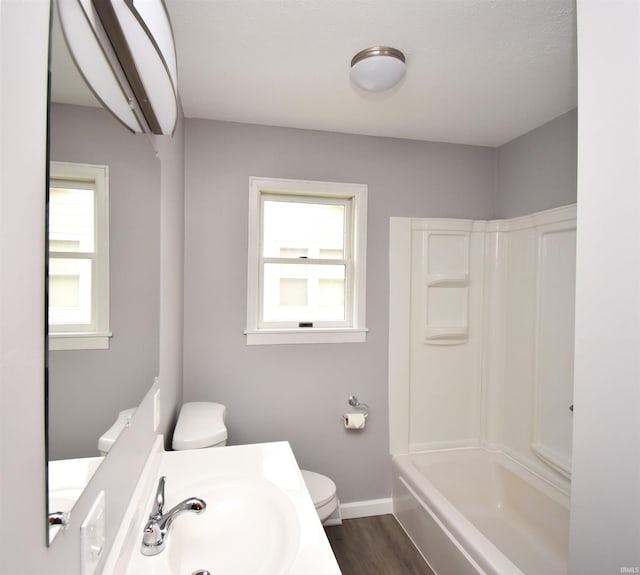 full bathroom featuring a wealth of natural light, washtub / shower combination, hardwood / wood-style floors, and toilet