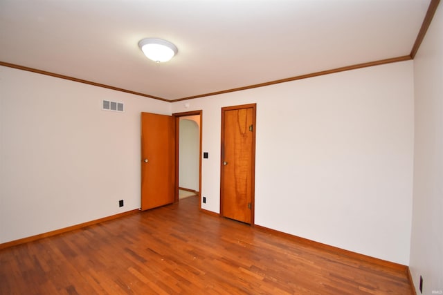 empty room featuring crown molding and hardwood / wood-style flooring