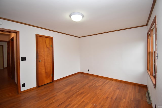 empty room featuring ornamental molding and hardwood / wood-style flooring