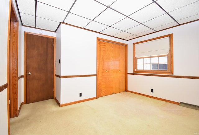 unfurnished bedroom featuring light carpet, a closet, and a drop ceiling