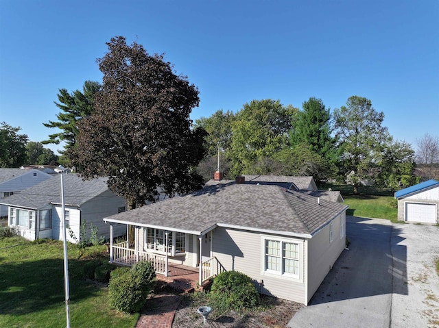 view of front of house with a garage, a front lawn, an outdoor structure, and a porch