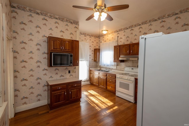 kitchen with backsplash, ceiling fan, white appliances, and dark hardwood / wood-style flooring