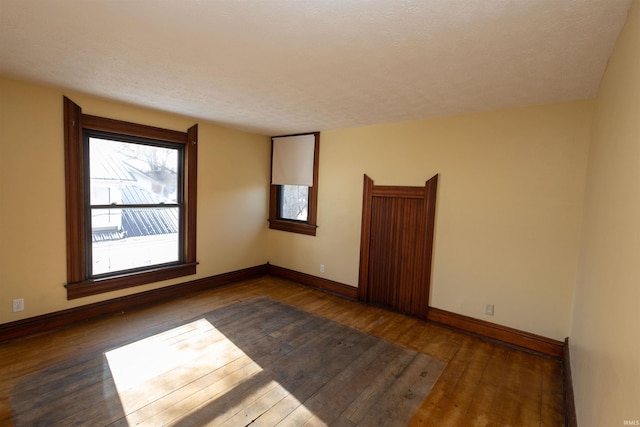 unfurnished room featuring dark hardwood / wood-style flooring and a textured ceiling