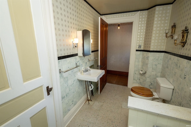 bathroom with toilet, tile floors, and tile walls