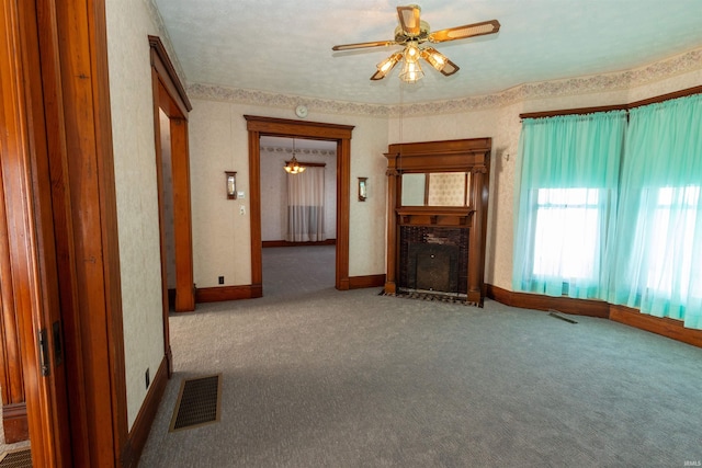 unfurnished living room featuring a textured ceiling, carpet floors, ceiling fan, and a brick fireplace