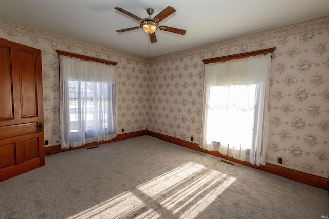 carpeted spare room with plenty of natural light and ceiling fan