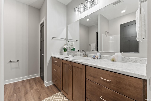 bathroom featuring walk in shower, vanity, and wood-type flooring