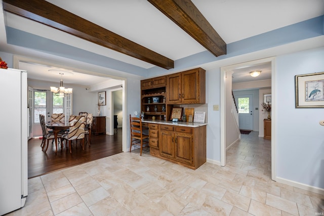 kitchen featuring white refrigerator, an inviting chandelier, hanging light fixtures, and a healthy amount of sunlight