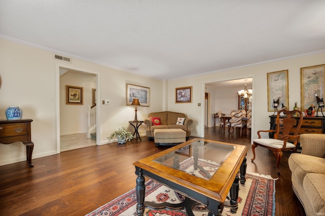 living room with dark hardwood / wood-style flooring, an inviting chandelier, and crown molding