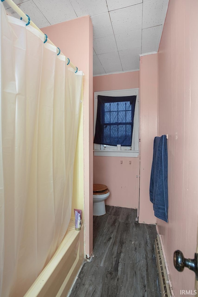 bathroom with toilet, baseboard heating, shower / bathtub combination with curtain, and hardwood / wood-style flooring