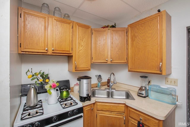 kitchen with stove, a drop ceiling, and sink