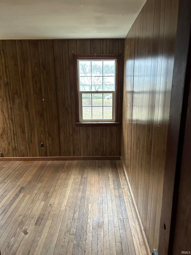 unfurnished room with light hardwood / wood-style floors and wood walls