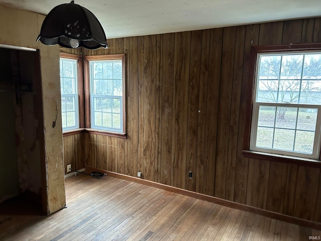 unfurnished bedroom featuring wooden walls, multiple windows, and wood-type flooring