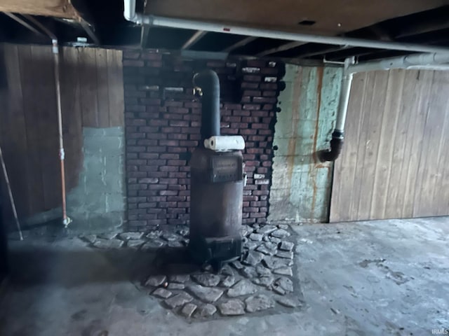 basement featuring a wood stove and brick wall