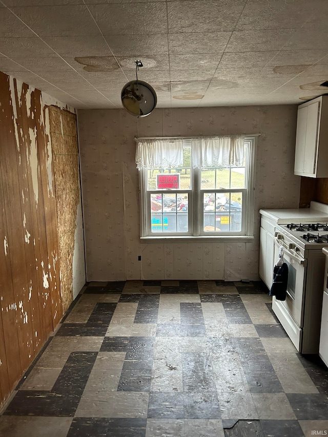 kitchen featuring gas range gas stove, dark tile floors, and white cabinetry